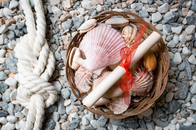 Primer plano de concha, letra y nudo marino en la orilla del mar