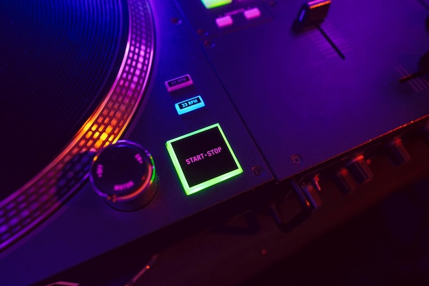 Un primer plano de la consola de mezcla de DJ en la luz de la fiesta