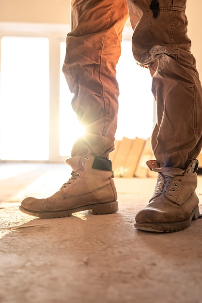 Primer plano de un constructor en ropa de trabajo y botas, primer plano, parte del cuerpo.