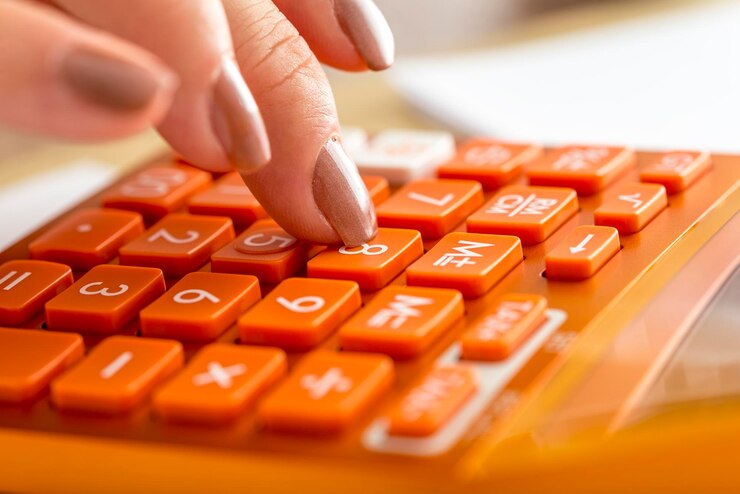 Foto primer plano de una contadora presionando el número ocho en una calculadora de escritorio naranja