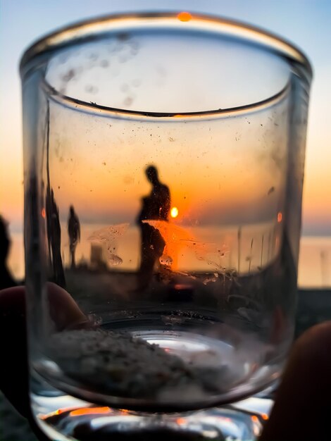 Foto primer plano de una copa de cerveza contra el cielo durante la puesta de sol