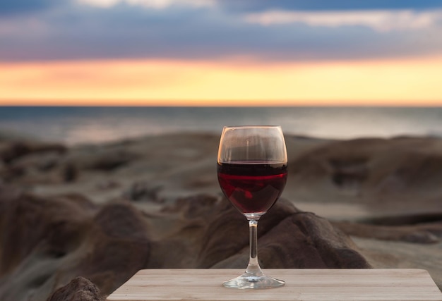 Primer plano de una copa de vino en la mesa contra el mar durante la puesta de sol