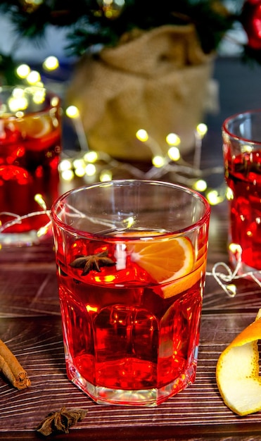 Primer plano de una copa de vino tinto caliente, sobre una mesa de madera con un árbol de Navidad