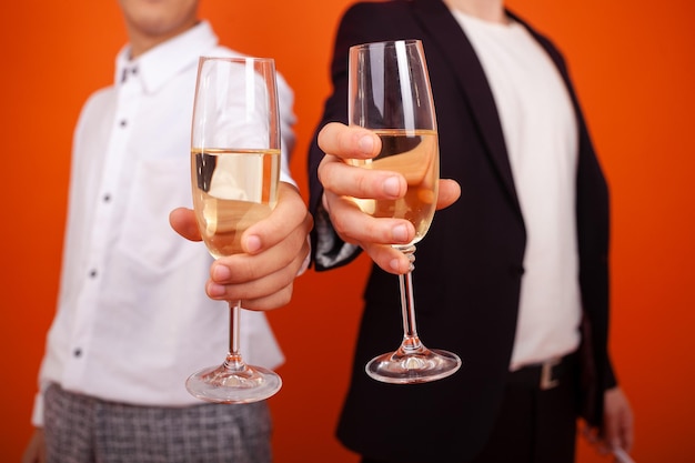 Primer plano de copas de champán tomados de la mano de hombres en ropa formal en una fiesta corporativa