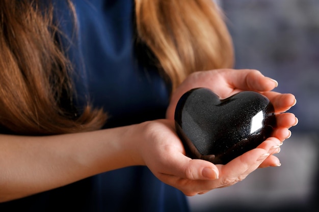 Primer plano de un corazón negro de cerámica en manos femeninas