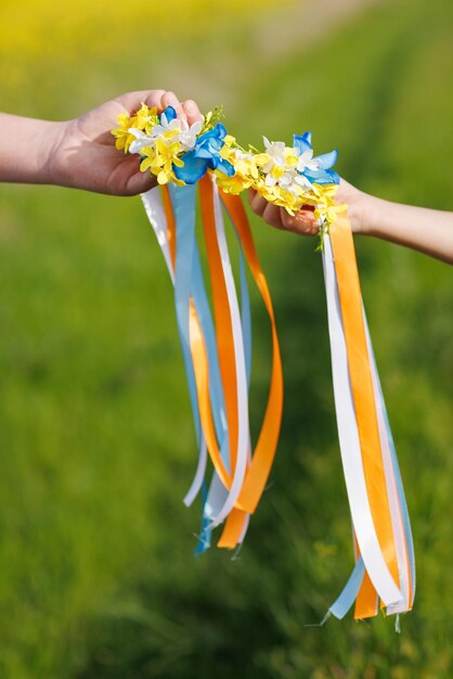 Primer plano de corona ucraniana con flores y cintas en manos de niños que trae esperanza para el fin de la guerra