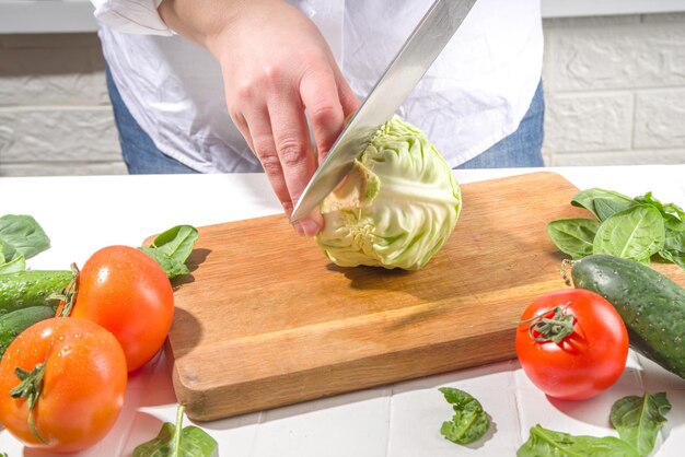 Primer plano de cortar rebanar repollo fresco Manos de mujer cortadas con cuchillo verduras de repollo fresco