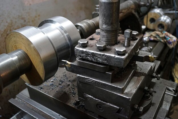 Primer plano de un corte de piezas de eje de metal por la vieja Maquinaria de torno mandril de torno y llave mandril de tornillo de 4 mordazas Maquinaria industrial vintage en una antigua fábrica