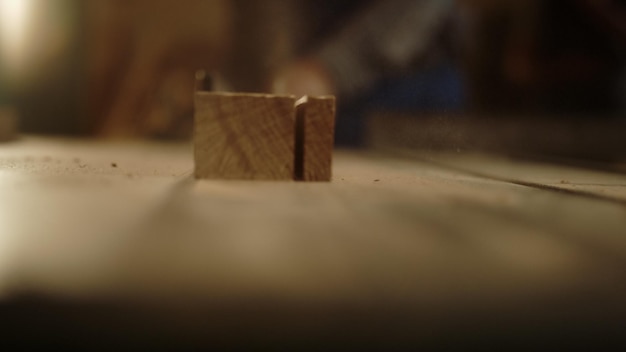 Primer plano de corte de tablones de madera en la máquina de sierra en el taller de carpintería Hombre desconocido que trabaja con madera en el estudio Chico no reconocido preparando el tablón en el interior