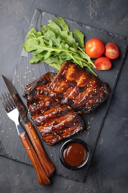 Primer plano de costillas de cerdo a la parrilla con salsa BBQ.