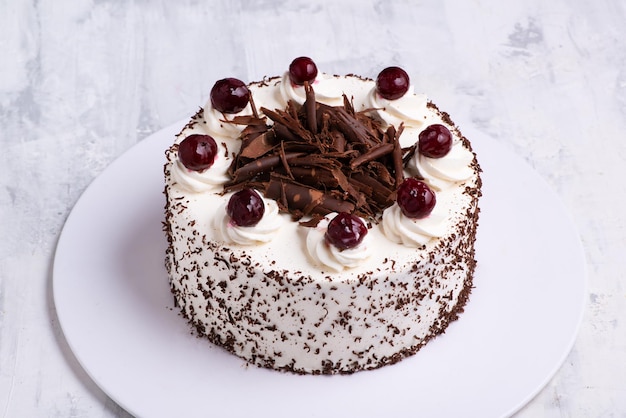 Un primer plano de crema blanca en el pastel de tarta de la Selva Negra con cerezas en la superficie de mármol blanco