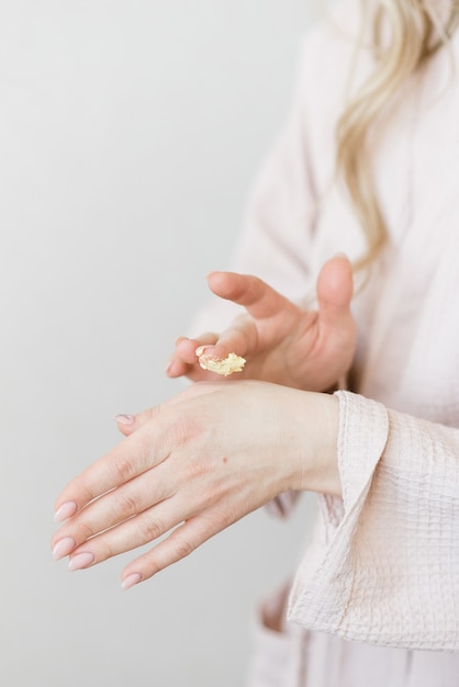 Primer plano de crema de frotis de manos femeninas hermosas sobre una crema de fondo blanco