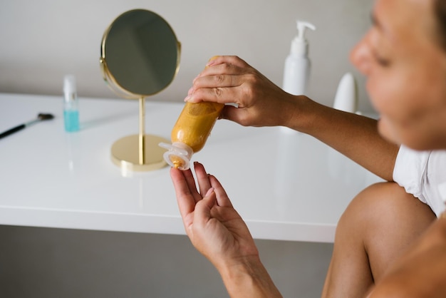 Primer plano de una crema hidratante de color dorado en manos de una mujer