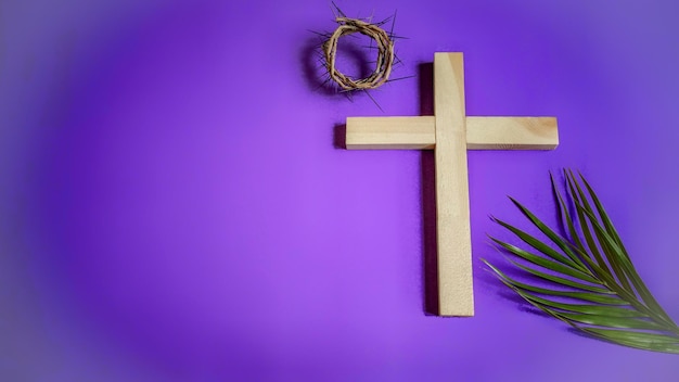 Primer plano de una cruz con hoja y corona sobre un fondo púrpura