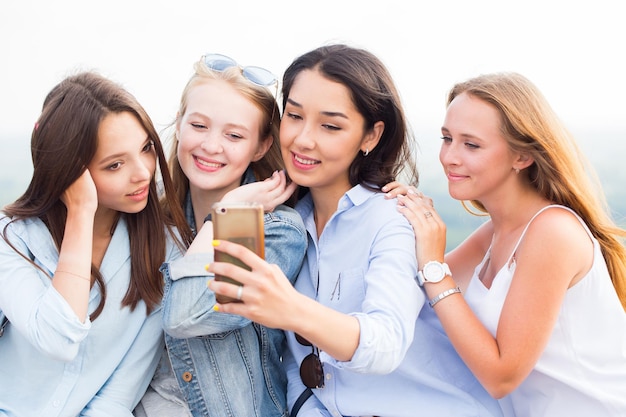 Primer plano de cuatro hermosas jóvenes estudiantes haciendo selfies y sonriendo