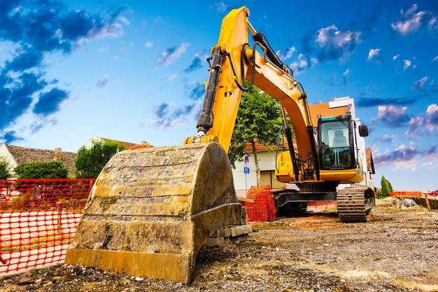 Primer plano de la cuchara de la excavadora en el sitio de construcción cielo azul soleado en el fondo Equipos de construcción para movimiento de tierras