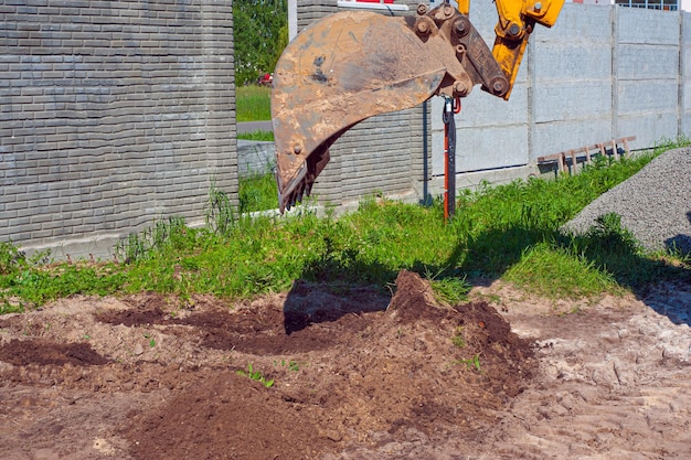 Primer plano del cucharón de la excavadora en el fondo de un sitio de construcción Equipo pesado de movimiento de tierras Desarrollo del suelo