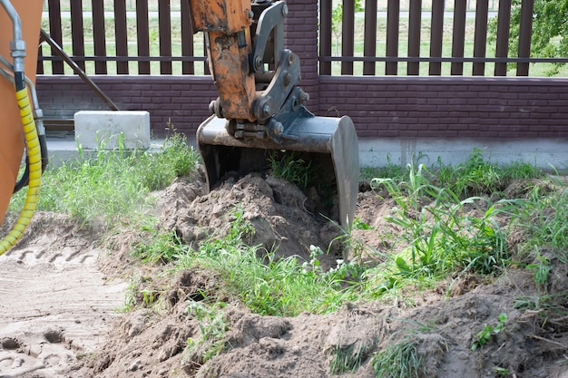 Primer plano del cucharón de la excavadora en el fondo de un sitio de construcción Equipo pesado de movimiento de tierras Desarrollo del suelo