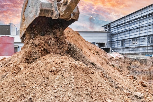 Primer plano del cucharón de la excavadora en el sitio de construcción La excavadora está cavando una zanja para servicios subterráneos Equipos de construcción para movimiento de tierras