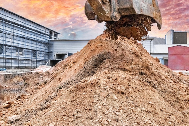 Primer plano del cucharón de la excavadora en el sitio de construcción La excavadora está cavando una zanja para servicios subterráneos Equipos de construcción para movimiento de tierras