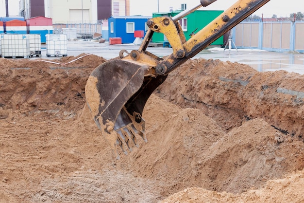 Primer plano del cucharón de la excavadora Trabajos de excavación en el sitio de construcción y construcción de carreteras Maquinaria de construcción