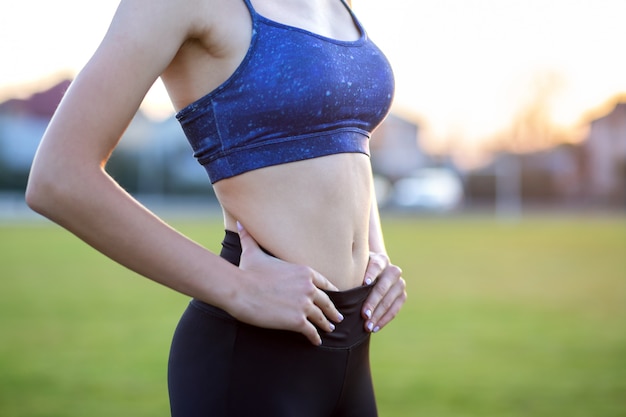 Primer plano de un cuerpo delgado de niña en ropa deportiva. Estómago plano como resultado del entrenamiento físico.