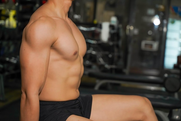 Primer plano y cuerpo perfecto de un chico asiático con entrenamiento con pesas en el gimnasio