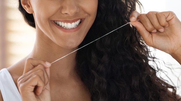 Foto primer plano de cuidado bucal de una joven sonriente usando hilo dental