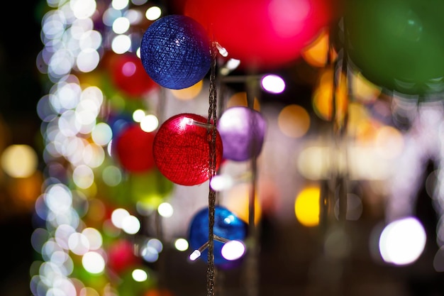 El primer plano y el cultivo decoran la bola tejida en Blurred y bokeh de la iluminación navideña y el fondo nocturno