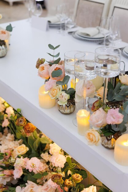 Un primer plano de una decoración de mesa de bodas con flores y velas blancas y rosas
