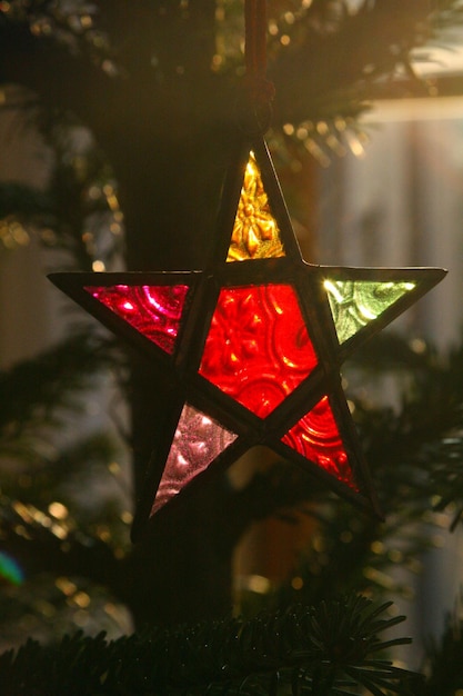 Primer plano de la decoración navideña en forma de estrella colgando en el árbol por la noche.