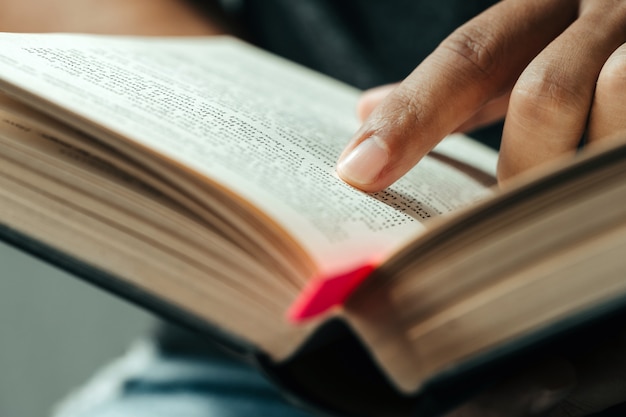 Primer plano del dedo señalando el texto en la Biblia. Cerca del hombre leyendo la Biblia.