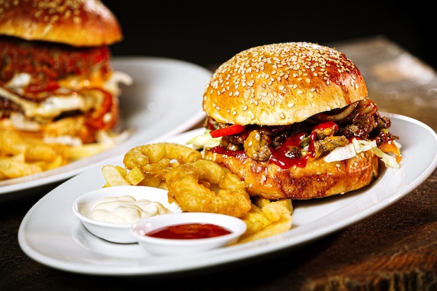 Primer plano de una deliciosa hamburguesa con papas fritas y aros de cebolla en una mesa de madera