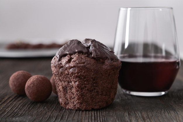 Foto primer plano de una deliciosa tarta de chocolate con trufas y vino tinto en la mesa de madera