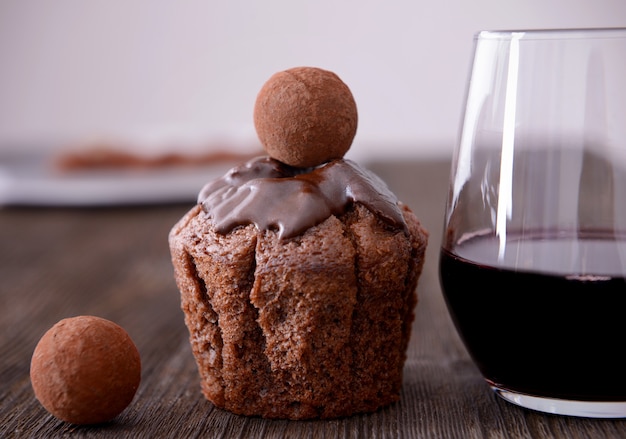 Primer plano de una deliciosa tarta de chocolate con trufas y vino tinto en la mesa de madera