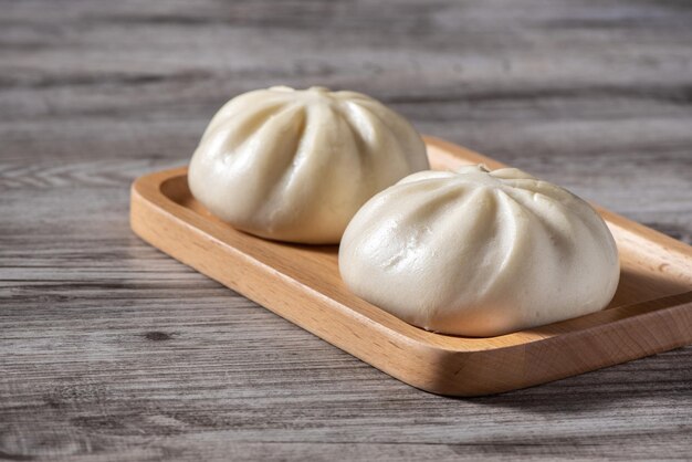 Foto primer plano del delicioso baozi fresco pan de carne al vapor chino está listo para comer en el plato de servicio y el vaporizador primer plano del concepto de diseño de producto del espacio de copia