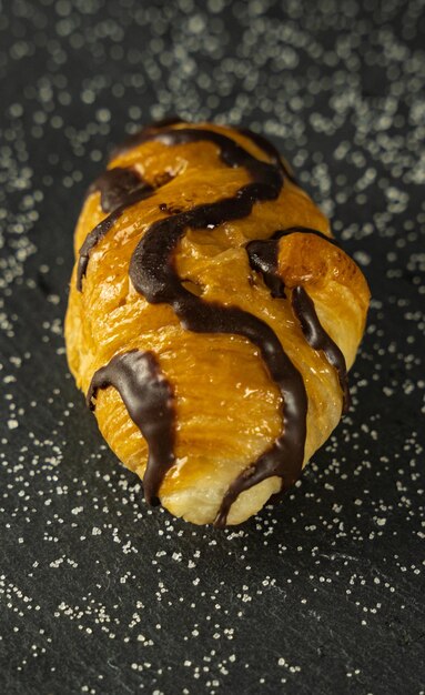 Primer plano de un delicioso croissant con chocolate en la parte superior contra un fondo oscuro