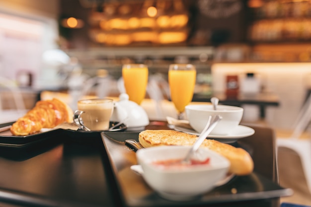 Primer plano de un delicioso desayuno, incluye zumo de naranja, pan tostado y un croissant.