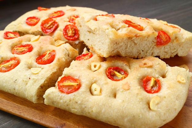 Primer plano de un delicioso pan casero de focaccia con tomate y ajo italiano