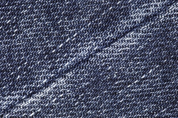 Primer plano de denim azul con unión de costura en un fondo de textura diagonalmente uniforme