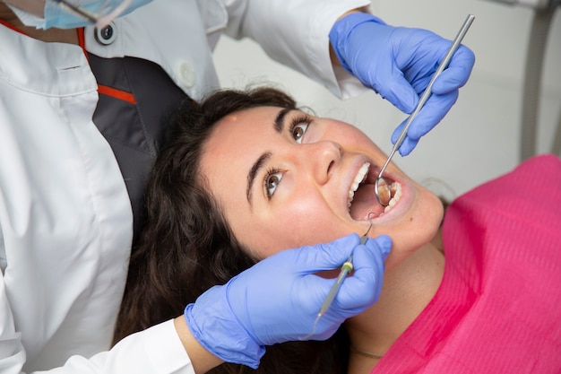 Primer plano de dentista trabajando en la boca de una niña.