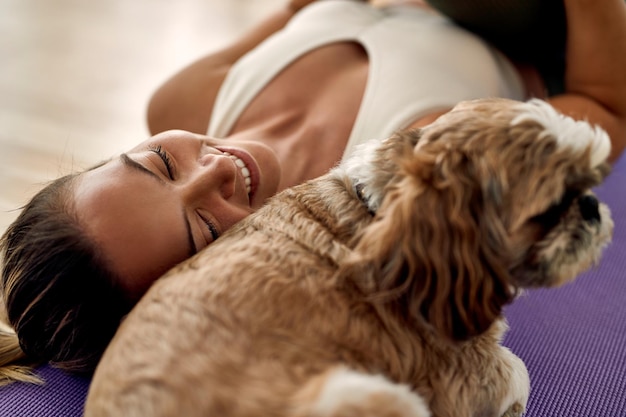 El primer plano de una deportista feliz y su perro descansando en el suelo