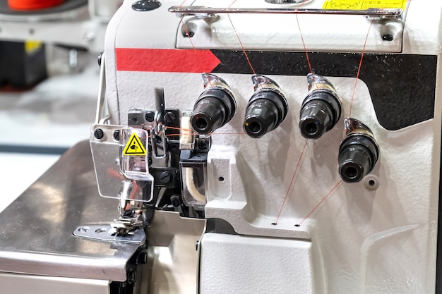 Primer plano de los detalles de la moderna máquina de coser eléctrica profesional blanca sobre una mesa en la fábrica. Lugar de trabajo de costurera. Nadie.