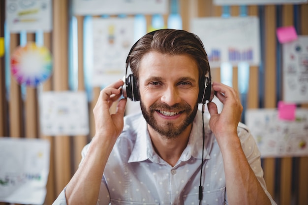 Primer plano de diseñador gráfico masculino escuchando música en auriculares