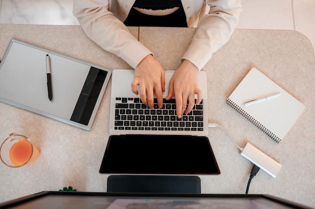 El primer plano de una diseñadora trabaja en la oficina en casa dibujando en una tableta gráfica Freelancer trabajando en un proyecto viendo una película en una computadora estudiando blogs relajándose y chateando en línea