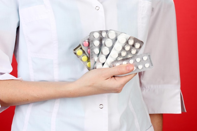 Primer plano de una doctora mano sujetando pastillas sobre fondo de color