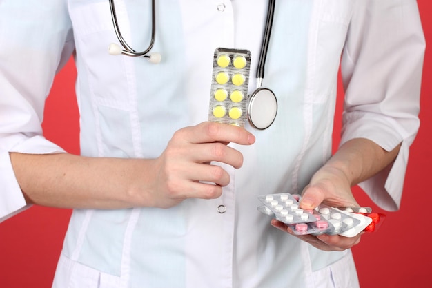 Primer plano de una doctora mano sujetando pastillas sobre fondo de color