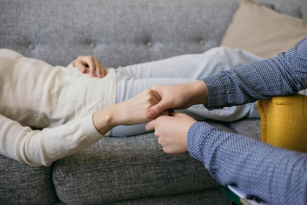 Foto el primer plano de una doctora psicóloga sostiene la mano del paciente en busca de apoyo. asistencia psicológica profesional. violencia doméstica