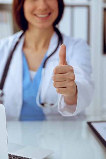 Primer plano de una doctora Thumbs up Feliz alegre sonriente morena médico listo para examinar al paciente Medicina concepto de atención médica y ayuda