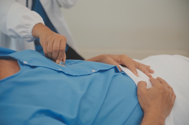 Primer plano de una doctora usando un estetoscopio para diagnosticar el latido del corazón con un paciente en la sala de examen de un cuerpo de chequeo hospitalario Concepto de atención médica y de salud